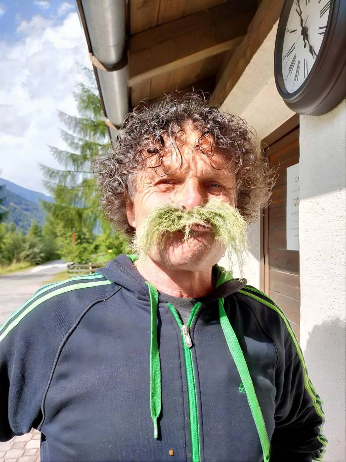 Die Biografie von Ruedi Weber ist alles andere als alltäglich. Als Landwirt, Historiker und Rockmusiker lebt er mit seiner Familie auf dem Trolerhof in Menziken AG, seine zweite Heimat jedoch ist das Val Müstair. Viele Wochen im Jahr verbringt er im Tal, wo er als «Flieger Ruedi» weitum bekannt ist. Mit seinem Gleitschirm schwebt er über die Berggipfel seiner Wahlheimat und sorgt mit seinen Landungen im Skigebiet Minschuns regelmässig für ein eindrückliches Schauspiel. Ebenso häufig ist er auf Bike-, Ski- und Wandertouren unterwegs. Vor genau 50 Jahren brachte ihn der Zufall erstmals nach Lü Daint. Seither kehrt er immer wieder ins Tal zurück, hat Freundschaften geschlossen und seine Frau auf der Alp Champatsch geheiratet. Das kleine Tiny House am Waldrand von Tschierv ist heute das zweite Zuhause der Familie Weber im Val Müstair.
