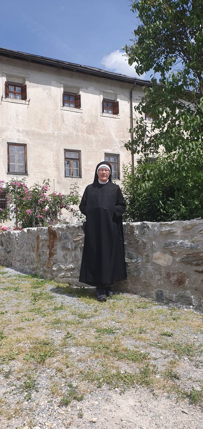 Schwester Maria Birgitta geniesst die warme Sonne vor ihrem Zuhause – dem Kloster St. Johann in Müstair.