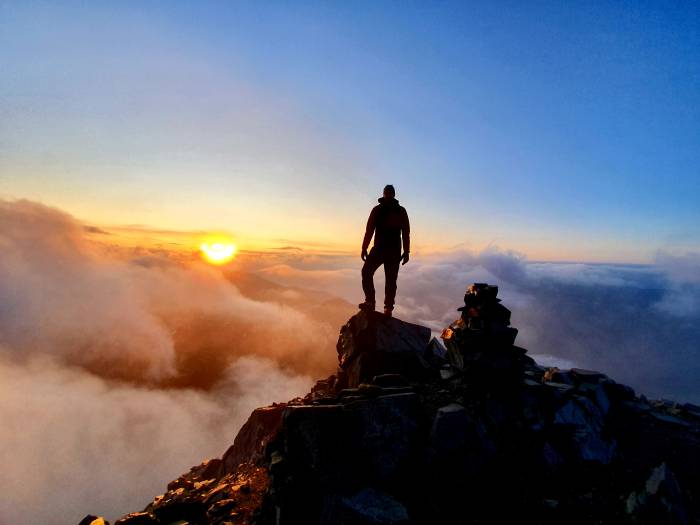 Fadri Furrer auf dem Gipfel des Piz Linard bei Sonnenaufgang. 